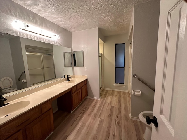 2934 Poplar Creek Ln, Pearland, TX 77584 - bathroom with wood finished floors, toilet, a shower stall, double vanity, and a textured ceiling