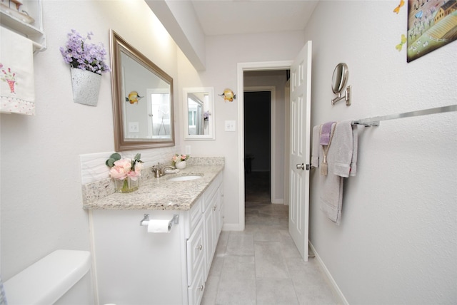 bathroom with toilet, vanity, tile patterned floors, and baseboards