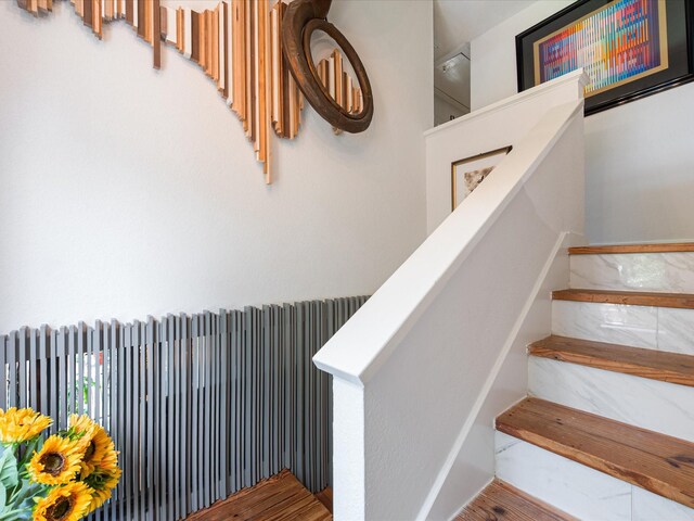 stairway with radiator, wood finished floors, and baseboards