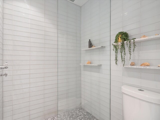 full bath with tiled shower, tile walls, and toilet