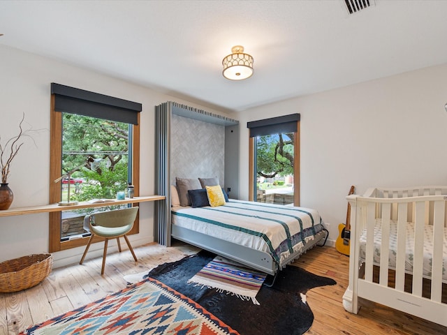 bedroom with multiple windows and wood finished floors
