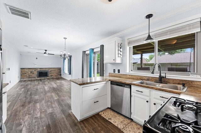 kitchen featuring dishwasher, a sink, black gas range, a peninsula, and a fireplace