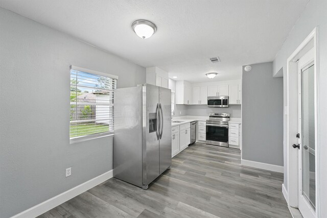 kitchen featuring appliances with stainless steel finishes, light countertops, baseboards, and white cabinets