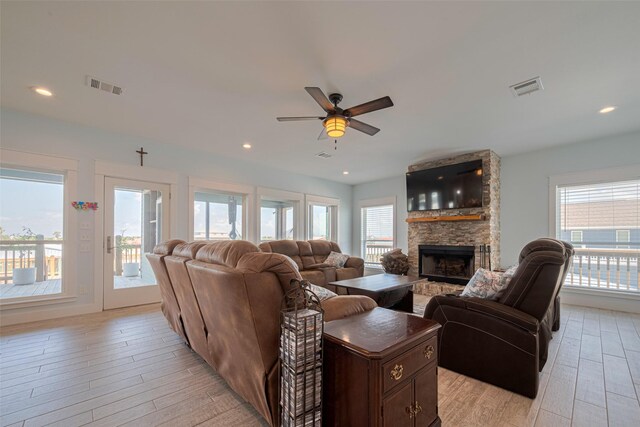 living room with a fireplace, light wood-style flooring, healthy amount of natural light, and a ceiling fan