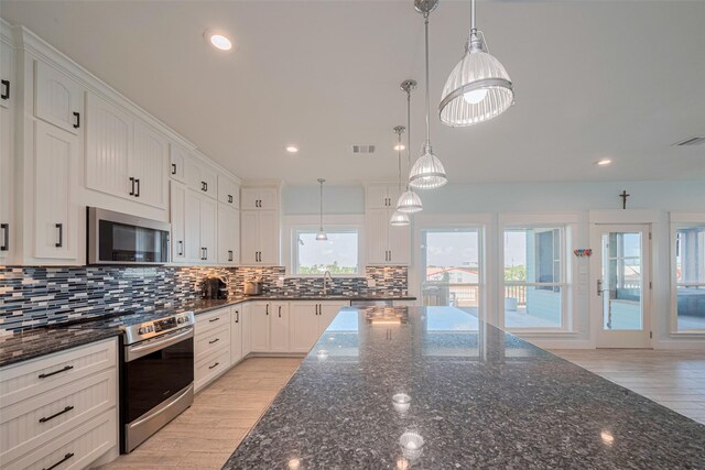 kitchen featuring appliances with stainless steel finishes, tasteful backsplash, white cabinets, light wood-style floors, and recessed lighting