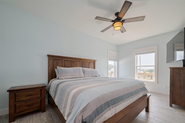 bedroom featuring light wood-type flooring, baseboards, and a ceiling fan