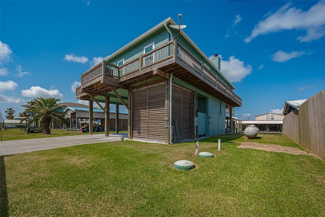 view of side of home featuring a yard, a wooden deck, a chimney, and driveway