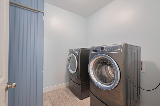 washroom featuring light wood-style flooring, baseboards, and independent washer and dryer