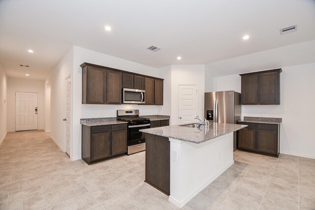 kitchen featuring appliances with stainless steel finishes, recessed lighting, dark brown cabinets, light stone countertops, and a sink
