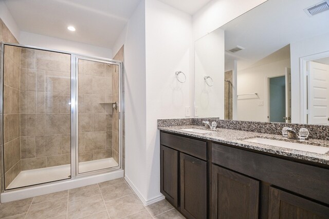 bathroom with a shower stall, tile patterned floors, double vanity, and baseboards