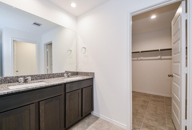 bathroom featuring a spacious closet, double vanity, baseboards, and tile patterned floors