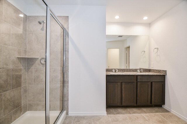 full bathroom with a shower stall, baseboards, double vanity, tile patterned flooring, and recessed lighting