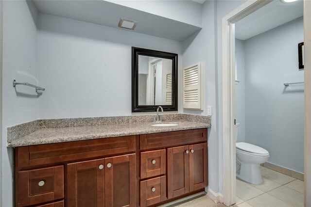 bathroom featuring toilet, tile patterned floors, vanity, and baseboards