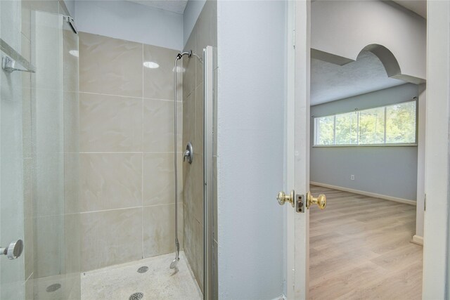 full bath featuring a shower stall, wood finished floors, and baseboards