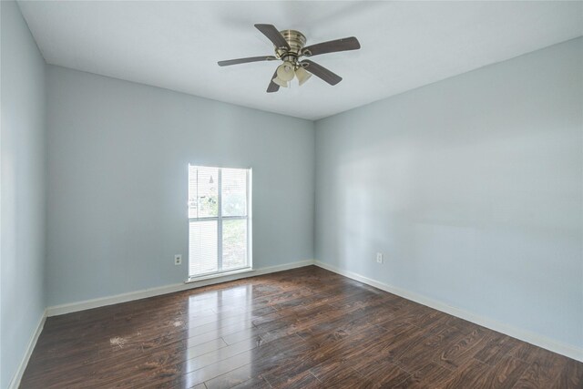 spare room featuring dark wood-style flooring, ceiling fan, and baseboards