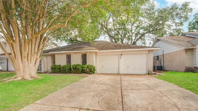 view of front facade with an attached garage, concrete driveway, a front lawn, central AC unit, and brick siding