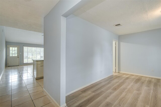 unfurnished room with baseboards, light wood-style floors, and a textured ceiling