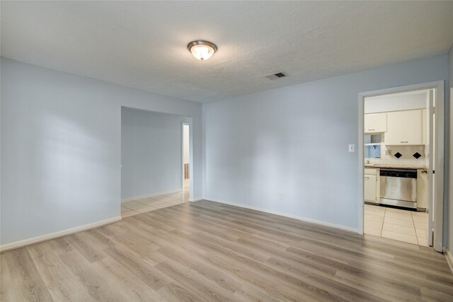 unfurnished room with light wood-type flooring, baseboards, and a textured ceiling