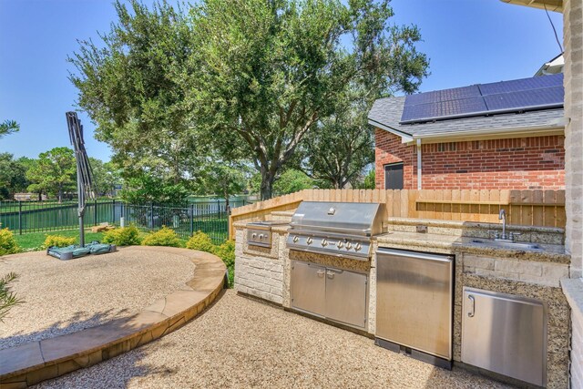 view of patio / terrace with a sink, grilling area, a fenced backyard, and an outdoor kitchen