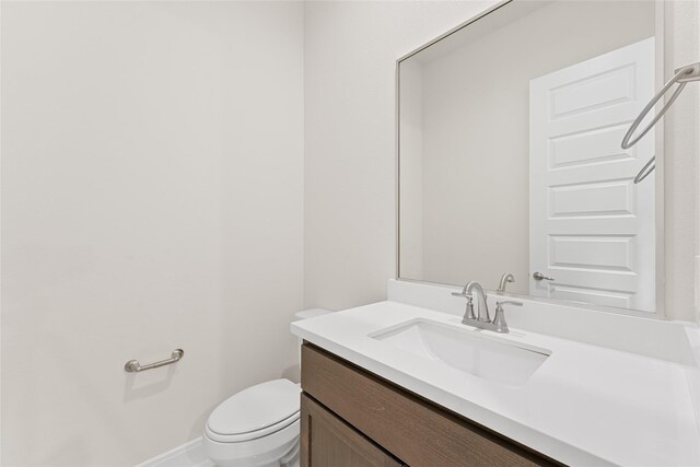 half bath with toilet, vanity, and baseboards