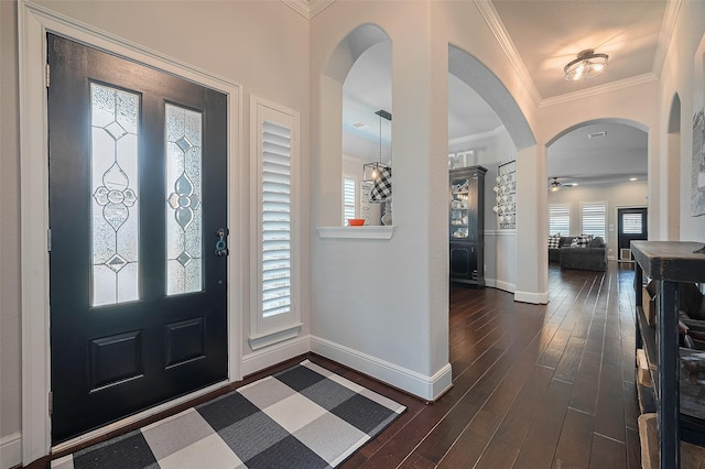 entryway with baseboards, arched walkways, dark wood-type flooring, and ornamental molding