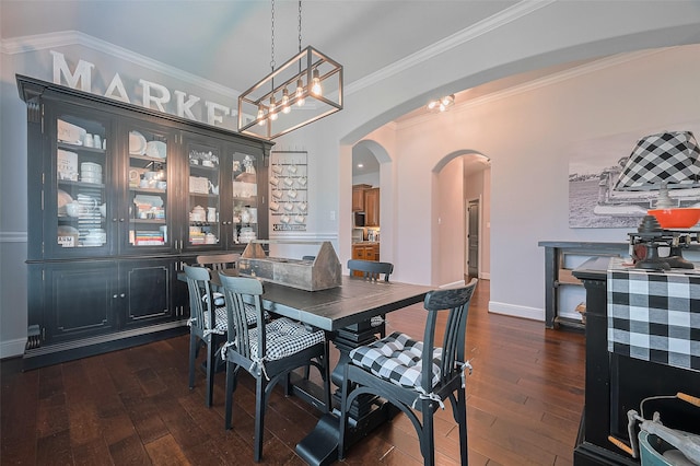 dining space featuring arched walkways, dark wood-style floors, crown molding, a chandelier, and baseboards