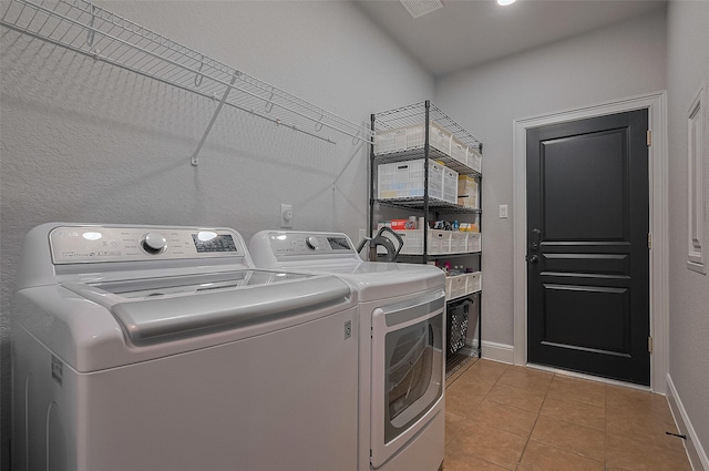 laundry area featuring separate washer and dryer, light tile patterned floors, and baseboards