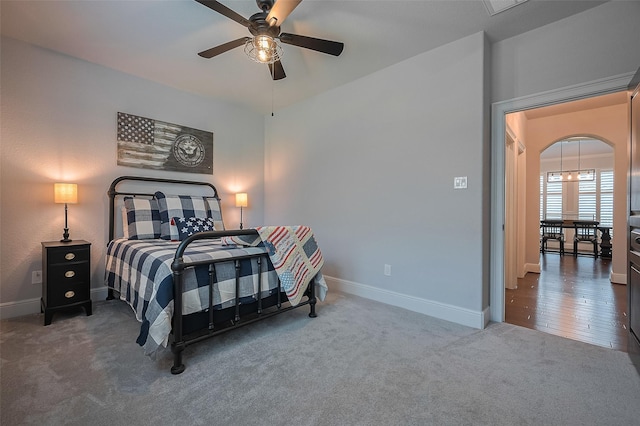 bedroom featuring carpet floors, baseboards, arched walkways, and ceiling fan