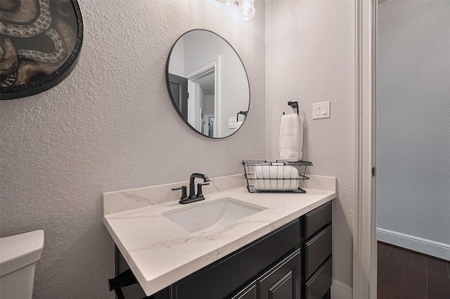 bathroom with wood finished floors, vanity, and toilet