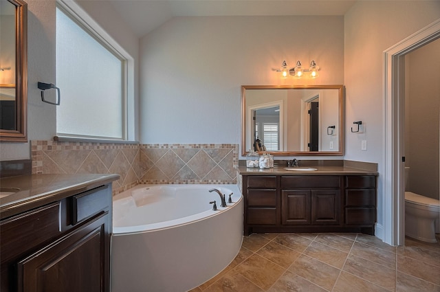 bathroom featuring plenty of natural light, toilet, a garden tub, vanity, and lofted ceiling