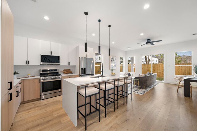 431 Neyland St, Houston, TX 77022 - kitchen featuring appliances with stainless steel finishes, a sink, light wood-type flooring, light countertops, and an island with sink