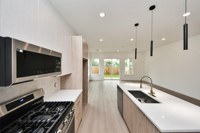431 Neyland St, Houston, TX 77022 - kitchen with stainless steel appliances, modern cabinets, light wood finished floors, a center island with sink, and backsplash