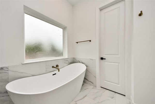 431 Neyland St, Houston, TX 77022 - full bathroom featuring marble look tiles, tile walls, a soaking tub, and a wainscoted wall