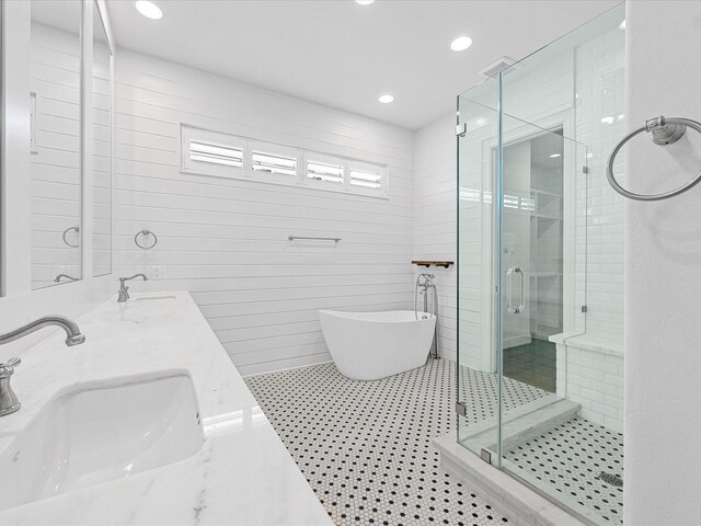 bathroom with a shower stall, a freestanding bath, double vanity, recessed lighting, and tile patterned floors