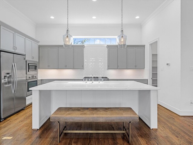 kitchen featuring appliances with stainless steel finishes, gray cabinets, a kitchen island with sink, ornamental molding, and recessed lighting