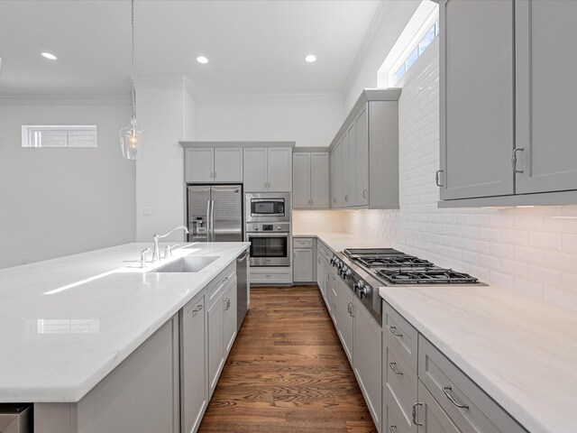 kitchen with stainless steel appliances, a sink, gray cabinets, ornamental molding, and backsplash