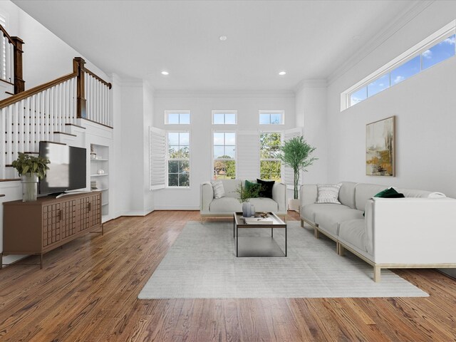 living room featuring ornamental molding, wood finished floors, stairs, a high ceiling, and recessed lighting