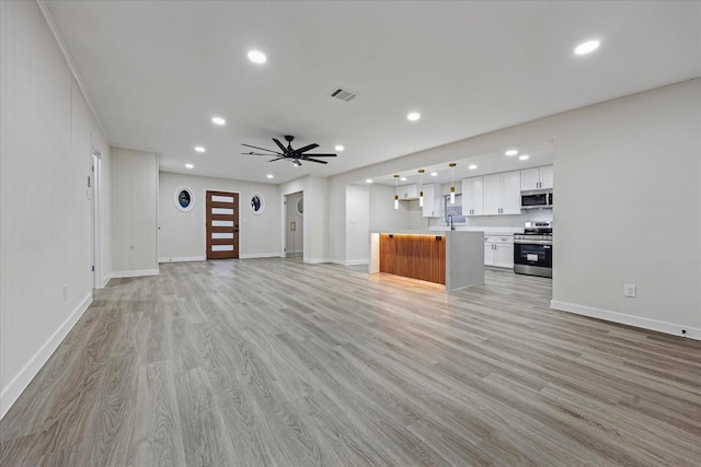 8902 Hendon Ln, Houston, TX 77036 - unfurnished living room with recessed lighting, light wood-type flooring, baseboards, a sink, and ceiling fan