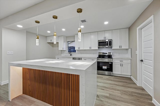 8902 Hendon Ln, Houston, TX 77036 - kitchen featuring appliances with stainless steel finishes, a sink, white cabinets, light wood-type flooring, and recessed lighting