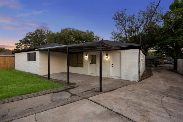 8902 Hendon Ln, Houston, TX 77036 - back of house at dusk with brick siding, driveway, a gate, and a carport
