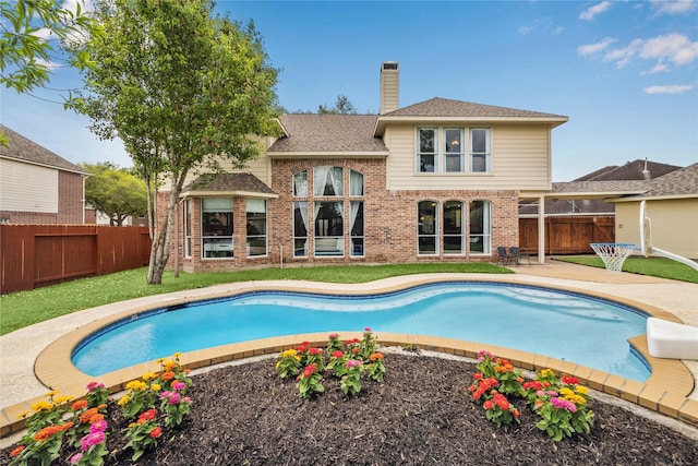 1703 Lakewinds Dr, Missouri City, TX 77459 - back of property featuring brick siding, a fenced backyard, a chimney, a patio, and a shingled roof