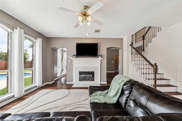 1703 Lakewinds Dr, Missouri City, TX 77459 - living room featuring arched walkways, dark wood-style floors, ceiling fan, stairs, and a textured ceiling