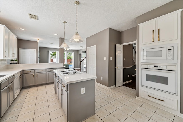 1703 Lakewinds Dr, Missouri City, TX 77459 - kitchen featuring white appliances, gray cabinets, light tile patterned floors, a peninsula, and light countertops