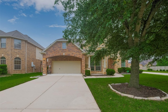 view of front of property featuring a front yard, driveway, brick siding, and a garage