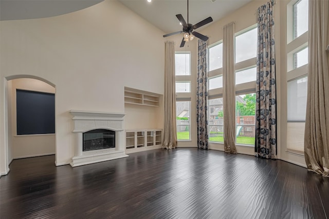 9968 Tallow Pointe Ln, Brookshire, TX 77423 - unfurnished living room featuring high vaulted ceiling, a ceiling fan, a glass covered fireplace, wood finished floors, and arched walkways