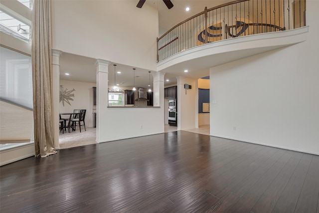 9968 Tallow Pointe Ln, Brookshire, TX 77423 - unfurnished living room featuring ornate columns, ceiling fan, wood finished floors, and a high ceiling