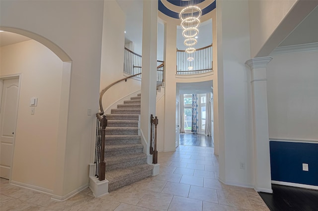 9968 Tallow Pointe Ln, Brookshire, TX 77423 - tiled foyer featuring stairway, a high ceiling, baseboards, arched walkways, and a chandelier