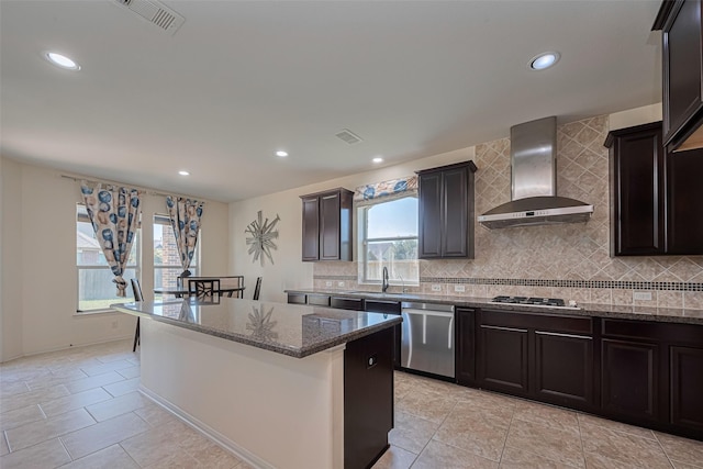 9968 Tallow Pointe Ln, Brookshire, TX 77423 - kitchen featuring appliances with stainless steel finishes, wall chimney range hood, a sink, dark stone counters, and a kitchen island