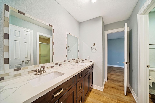 3726 Straightfork Dr, Houston, TX 77082 - bathroom with wood finished floors, a shower stall, double vanity, baseboards, and a textured wall