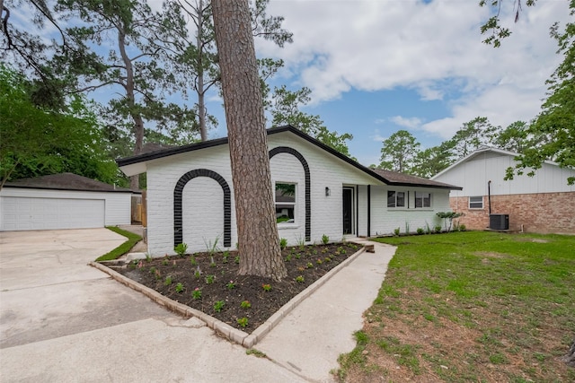 ranch-style home featuring brick siding, an outbuilding, a detached garage, a front yard, and central air condition unit